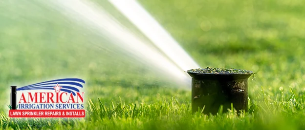 Pop-up sprinkler head watering a lawn with the American Irrigation Services logo