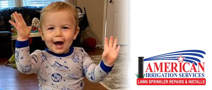 Smiling toddler waving with the American Irrigation Services logo